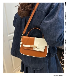 Detail of two-tone brown and cream Kelly bag with gold twist lock on denim outfit