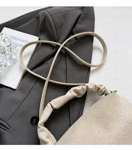 Detail of cream-colored lychee textured leather bag with unique pleated cloud shoulder strap