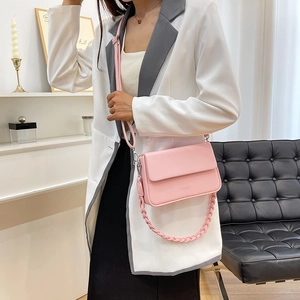 Sac bandoulière en cuir rose clair avec deux sangles porté par un mannequin dans un salon