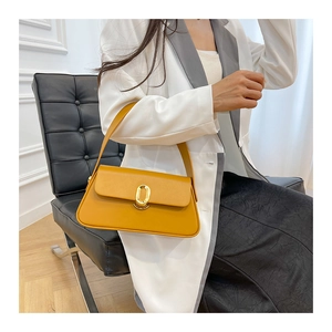 Detail of ginger yellow leather square bag with gold oval buckle and matching strap