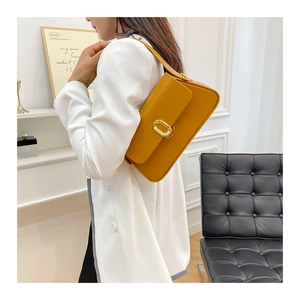 Detail of trendy mustard yellow leather baguette bag with shiny gold oval metal clasp