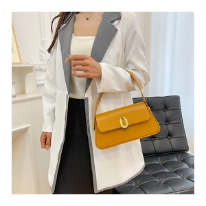Detail of yellow leather crossbody bag with elegant golden metal oval twist lock buckle