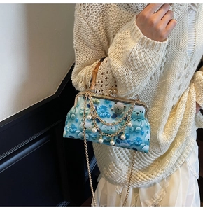 Detail of blue doctor bag featuring 3D teddy bear print, bamboo handle, and pearl chain