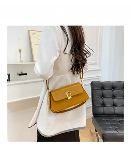 Detail view of mustard yellow leather baguette bag with gold metal swivel lock and strap