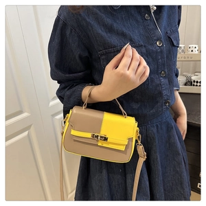 Detail of color-block saddle bag featuring golden metal turn-lock and adjustable strap