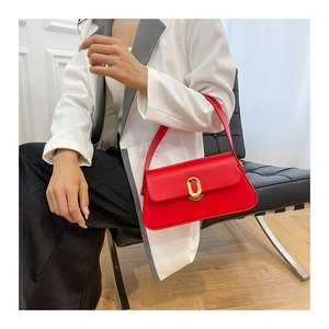 Detailed view of the bright red leather shoulder bag with a gold oval metal clasp