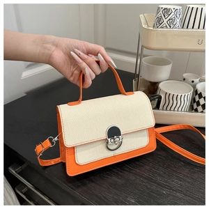 Detail of contrast color mini bag with canvas texture and orange leather accents