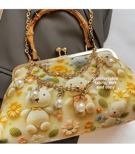 Detailed shot of retro bag with bamboo handle, pearl chain, and soft crochet pattern