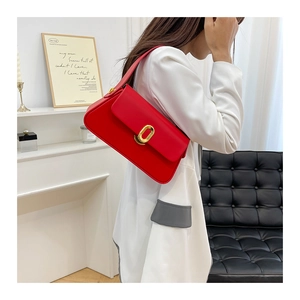Close-up of vibrant red crossbody bag with elegant gold oval lock on a leather flap