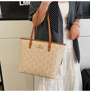 Detail of printed canvas tote bag featuring brown leather trim and golden kangaroo logo