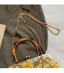 Detail of bamboo handle and gold chain strap on floral shell bag with bear pattern