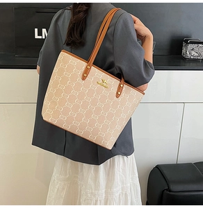 Detail of beige jacquard tote bag with brown leather trim and metal kangaroo logo
