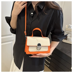Close-up of contrast color handbag with orange leather trim and woven canvas texture