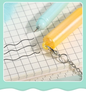 Detailed view of fine tip ballpoint pen with metallic chain hook and blue ink strokes