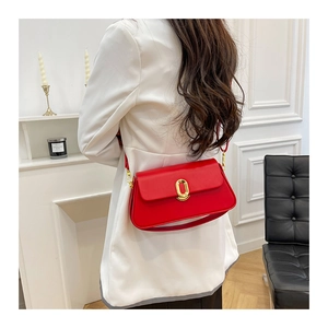 Detail view of a red leather square crossbody bag with a gold oval twist lock on a model