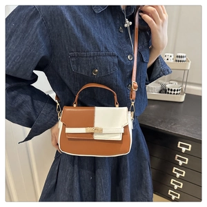 Detail of a contrast color crossbody bag featuring brown and white PU leather and gold buckle