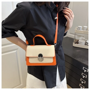 Detail of orange and beige contrast handbag with canvas texture and metal twist lock