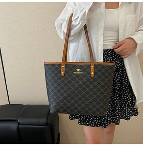 Close-up of a large tote bag with monogram print and golden kangaroo logo on shoulder