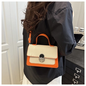 Detail view of contrast color crossbody bag with orange leather and canvas textures