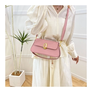 Detail shot of pale pink flap bag with gold oval lock on a model in white dress