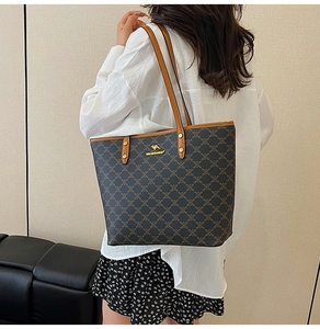 Detailed view of monogrammed large tote bag with leather handles shown on shoulder
