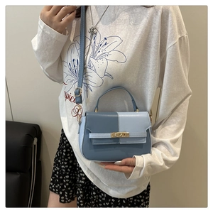 Detail of a two-tone blue crossbody Kelly bag featuring a gold metal twist lock closure