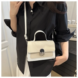Detail view of contrast stitch square bag with straw weave and white leather strap