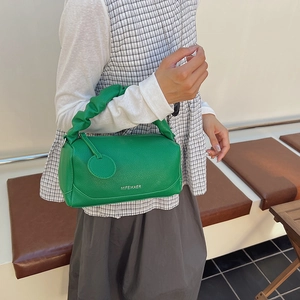 Green leather Boston bag with ruched handles and silver logo on a textured surface