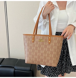 Detail of large brown tote bag with logo pattern and golden kangaroo hardware