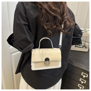 Detail of the woven texture and metallic arc rotary lock on this bicolor crossbody bag