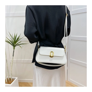 Detail of white rectangle flap bag with elegant gold oval metal clasp and slim strap