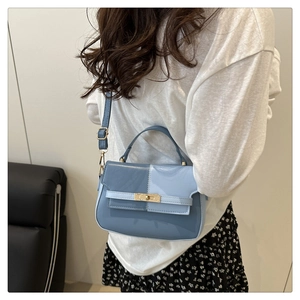 Detail of blue two-tone patent leather mini bag with gold buckle and slim shoulder strap