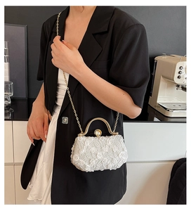 Detailed shot of white lace evening clutch bag with gold handle and beaded clasp