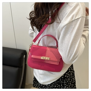 Detailed view of rose pink leather handbag with gold metal clasp on a female model