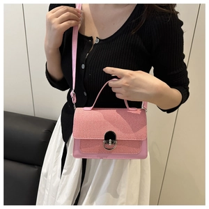 Detail of pink crossbody bag with woven texture lid and metal oval lock on leather