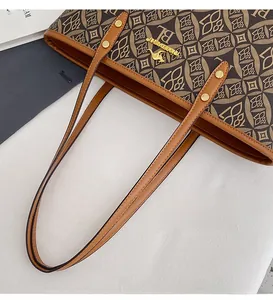 Close-up of the long dual handles and metallic rivet details on a brown leather tote bag