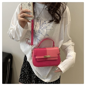 Detail of a two-tone pink leather crossbody bag featuring a metal lock and adjustable strap