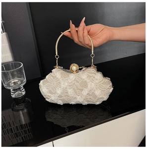 Close-up of beige lace floral clutch with golden metal ring handle and pearl clasp decor