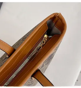 Close-up of golden kangaroo logo zipper pull and brown monogram fabric on tote bag