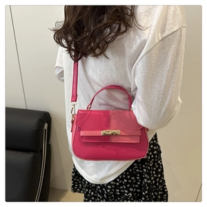 Detail of fuchsia leather handbag with gold buckle and vertical stitching on model