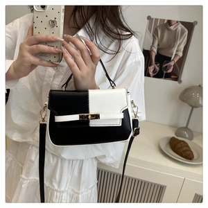 Detail of a color-block saddle bag with golden twist lock and textured PU leather