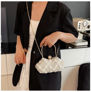 Lace flower evening bag with pearl clasp, metal handle, and chain worn by a model
