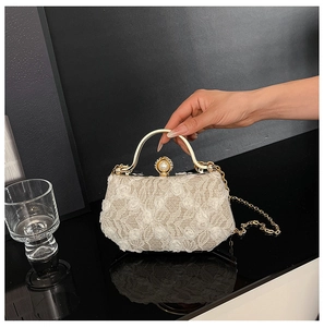Detailed macro view of 3D lace floral applique and pearl clasp on white evening box bag