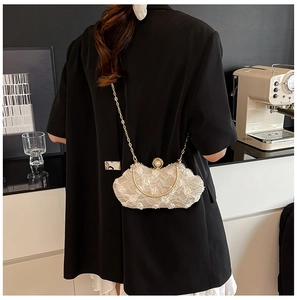 Detailed shot of white floral lace evening bag with pearl clasp and chain strap