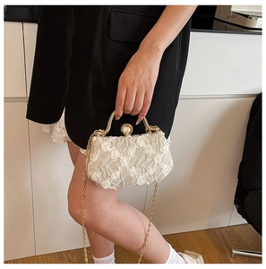 Detailed view of beige lace evening clutch with floral 3D texture and gold metal chain