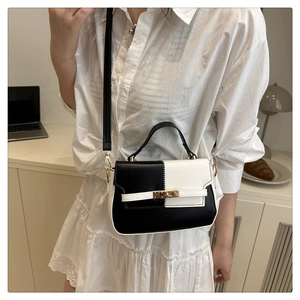 Detail of a chic black and white contrast handbag with golden twist lock and long strap