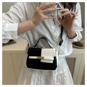 Detail view of monochrome Kelly bag with gold metal hardware and adjustable strap