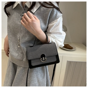 Detail of grey and black color-block crossbody bag with vintage metal clasp and strap