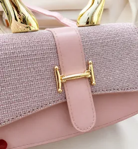 Macro view of pink textured leather handbag featuring a golden H-shaped clasp buckle