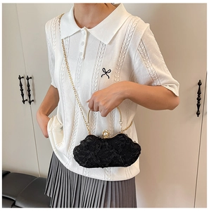 Detail of black lace evening bag with gold metal handle and elegant pearl clasp on model